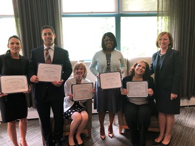 Bank employees with their diplomas and Bank President & CEO Gilda Nogueira