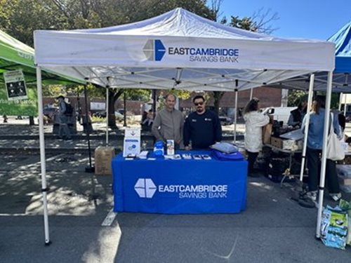 Bank employees standing at a table under a tent at the Union Square Farmers Market in Somerville on October 8, 2022.